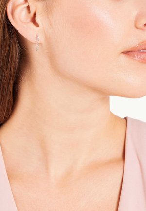 Boucles d'oreilles en argent ornées de trois petites sphères et d'une délicate chaîne. Le design est minimaliste avec une finition polie.