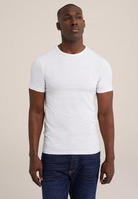 Witte katoenen t-shirt met korte mouwen, gemaakt van soepele katoen, met een ronde hals en een aansluitende pasvorm, gecombineerd met blauwe denim jeans.