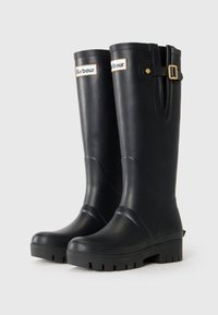 Pair of black knee-high rubber boots with thick soles and gold buckle detail near the top, labeled with Barbour logo.