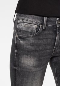 Pantalones vaqueros negros de mezclilla con un acabado descolorido, marca G-Star en el bolsillo delantero y detalles de herrajes estándar.