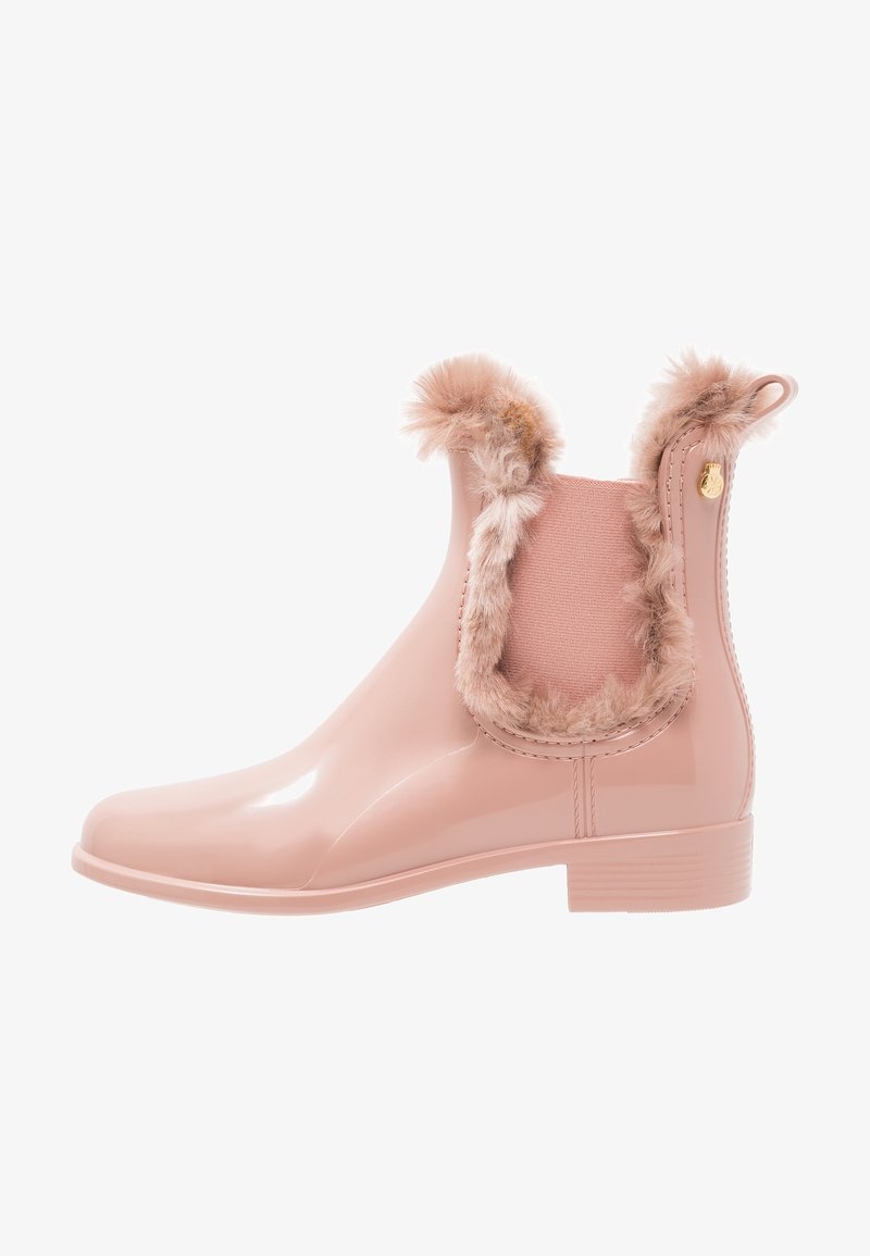 Bota de lluvia de tobillo de color rosa pálido brillante con ribete de piel sintética alrededor del panel lateral elástico y la parte superior, tacón bajo y tirador en la parte posterior.