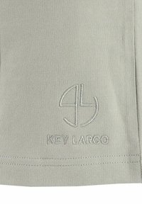 Lichtgrijze stof met een gladde textuur, met een geborduurd logo "KEY LARGO" en een cirkelontwerp. Eenvoudige, casual stijl met strakke lijnen.