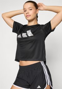 Black short-sleeve athletic top featuring a textured graphic pattern in white. Paired with black shorts with white accents and stripes.