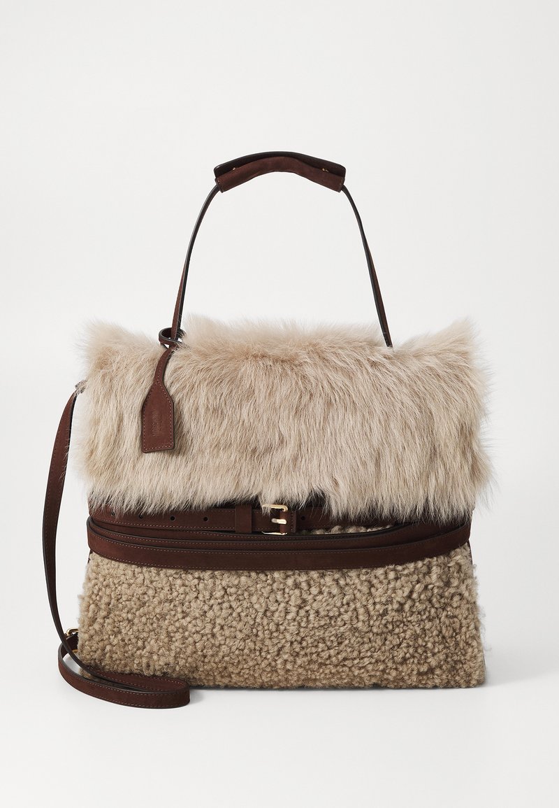 Sac en fausse fourrure avec un dessus duveteux beige clair, des accents en cuir marron, une poignée supérieure et une bandoulière amovible. Section inférieure texturée.