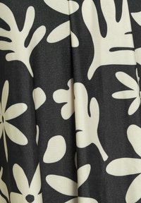 Svart tyg med ett vitt blommönster och blad. Texturen är slät med en lätt lyster som skapar kontrast i designen.