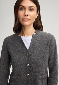 Blazer grigio in pura lana con una sottile texture, dotato di colletto a scollo a V, quattro bottoni metallici e due tasche frontali.