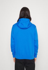 Blå sweatshirt med huva, som har en mjuk textur och ribbade muddar. Enkel design, utan synliga mönster eller dekorationer.