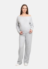 Grauer schulterfreier Pullover und passende lockere Hose aus weichem Stoff. Merkmale sind eine entspannte Passform und lange Ärmel, getragen über einem runden Bauch.