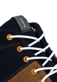 Buty z mieszanki wełny z ciemnoniebieskimi i brązowymi panelami, białymi sznurowadłami, żółtymi oczkami i szarym znaczkiem logo na pięcie.