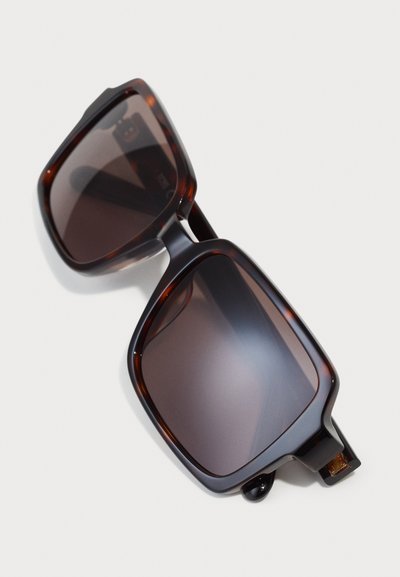 Tortoiseshell sunglasses with oversized square lenses, dark tinted, featuring thick frames and subtle gold accents on the arms.