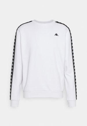 Sudadera blanca con mangas largas, puños acanalados y cuello redondo. Presenta franjas negras laterales con un patrón repetido de logotipos. Tejido texturizado.