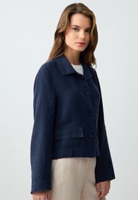 Marineblauwe linnen blazer met een kraag, knoopsluiting en twee voorkanten zakken. Heeft recht gesneden mouwen en een relaxte pasvorm.