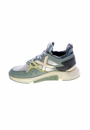Zapatilla deportiva en azul claro, gris y verde. Cuenta con materiales de malla y gamuza, una suela texturizada y un logo prominente en el lateral.