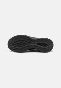 Svart treningssko såle med teksturert gummi for grep, med bølget design og spor for ekstra grip og fleksibilitet.