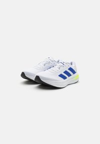 White athletic shoes with blue accents and a black sole. Made from mesh material with a sleek design and a bright yellow heel detail.