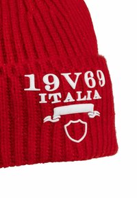 Rode gebreide beanie met witte bedrukte tekst "19V69 ITALIA" en een schildgrafiek, met een geribbelde textuur en omgeslagen rand.