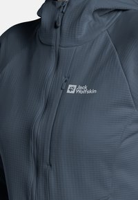 Veste légère à capuche en gris foncé avec un motif texturé, fermeture éclair intégrale et logo sur la poitrine.