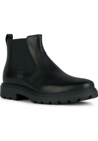 Botas de cuero negras hasta el tobillo con paneles laterales elásticos, puntera redonda y suela de goma negra resistente con surcos de tracción.
