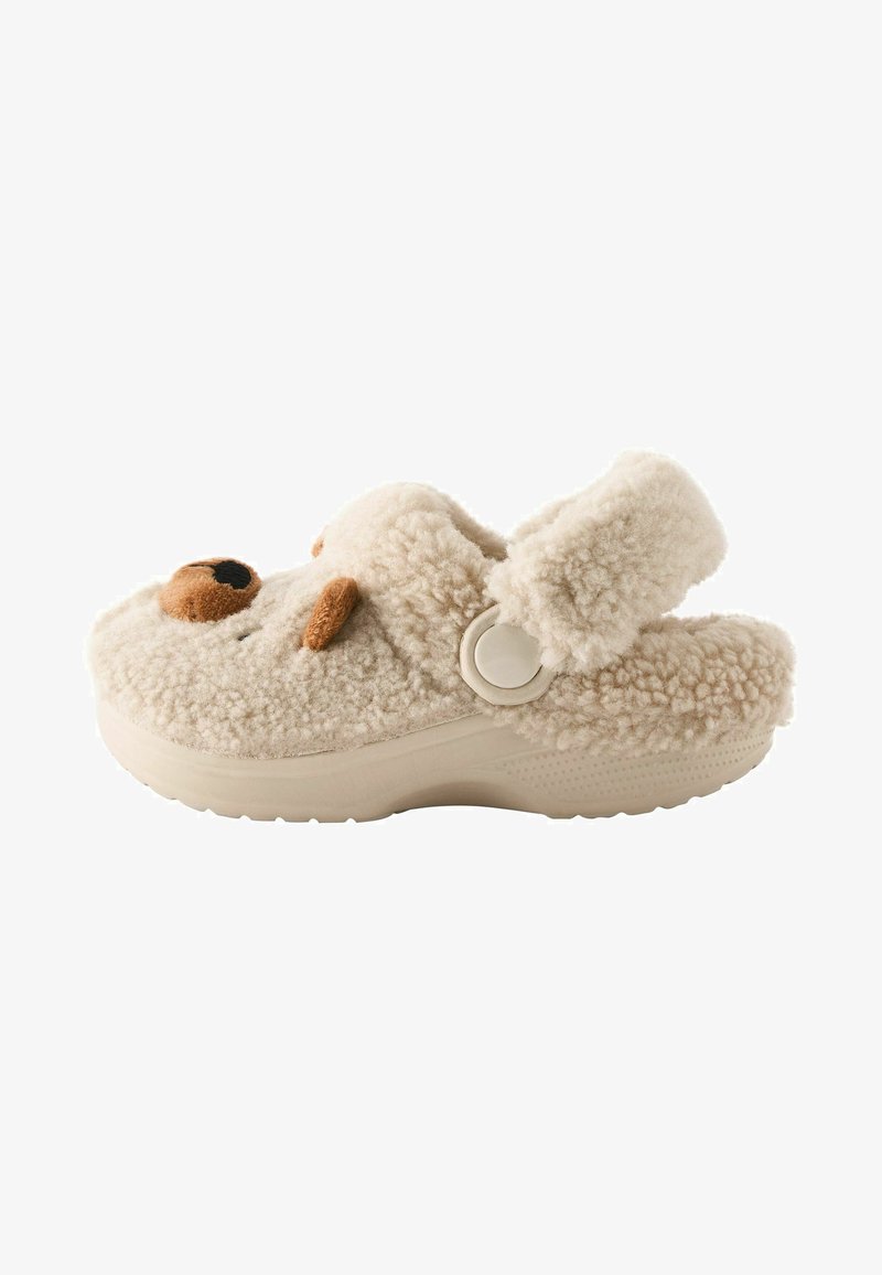Flauschiger beiger Hausschuh mit Bärenkopfdetails, strukturiertem Außenmaterial, verstellbarem Riemen und gepolsterter Sohle für Komfort.