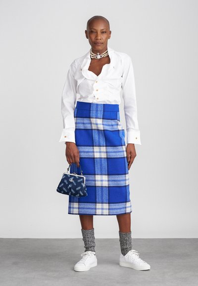 Valkoinen paita kukkakauluksella, sinivuorinen villahame, harmaat neulotut sukat ja valkoiset tennarit. Pieni sininen käsilaukku kukkakuviolla.