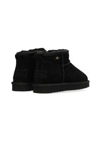 Svarta mockaimitation ankboots med en mjuk innerfoder, rund tå, platt gummisul och dekorativ söm. Gyllene logotypaccent på sidan.