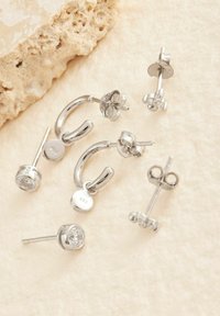 Conjunto de pendientes de plata que incluye diseños de perno y aro. Incluyen detalles con piedras transparentes, marcados con "925" que indica calidad de plata esterlina.