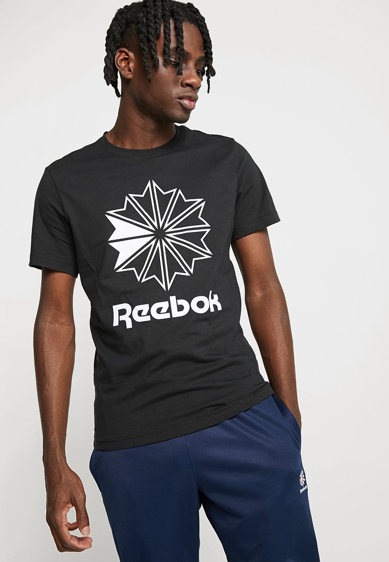 T-shirt in cotone nero con una grande grafica di una stella bianca e la parola "Reebok" in grassetto bianco sul lato anteriore. Maniche corte, scollatura rotonda.