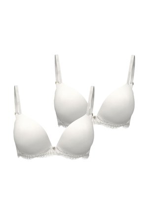 Dvě bílé podšité podprsenky s nastavitelnými ramínky a krajkovou lemovkou podél spodních okrajů, zobrazené na jednobarevném pozadí.
