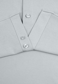 Grijze polo shirt met een textuurstof, een drieknoopsluiting en een klassieke kraag. Het ontwerp is uniform en naadloos.