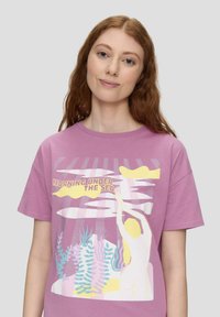 Lavendel Baumwoll-T-Shirt mit einem grafischen Design, das Ozeanelemente darstellt, darunter Seegras, einen Schwimmer und stilisierte Sonnenstrahlen.