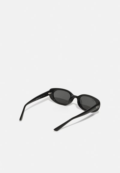 Lunettes de soleil noires avec une finition brillante, de forme ovale, verres sombres et branches fines avec un logo discret sur le côté.