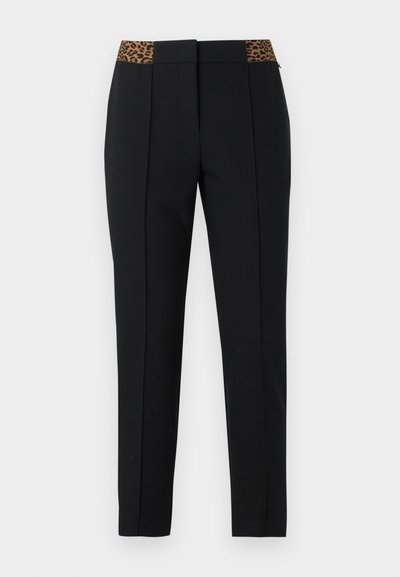Pantalon noir slim avec plis devant et détail ceinture imprimé léopard, présenté sur un fond clair.