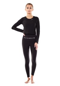Black long-sleeve crop top with round neckline; paired with high-waisted leggings featuring decorative pattern around waistband. Soft, stretchy fabric.