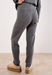Pantaloni a coste grigi con una vestibilità slim, dotati di una vita elasticizzata e caviglie con risvolto. Abbinati a scarpe con plateau beige.