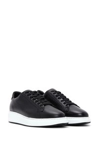 Sneakers in pelle nera con punta arrotondata, design con lacci e suola in gomma bianca. Texture liscia con dettagli minimi e cuciture a contrasto.
