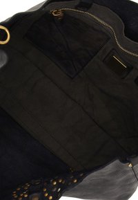 Interno di una borsa in pelle nera con una texture liscia, dotato di una cerniera dorata, una fodera in tessuto scuro e una tasca e un'etichetta aggiuntive.
