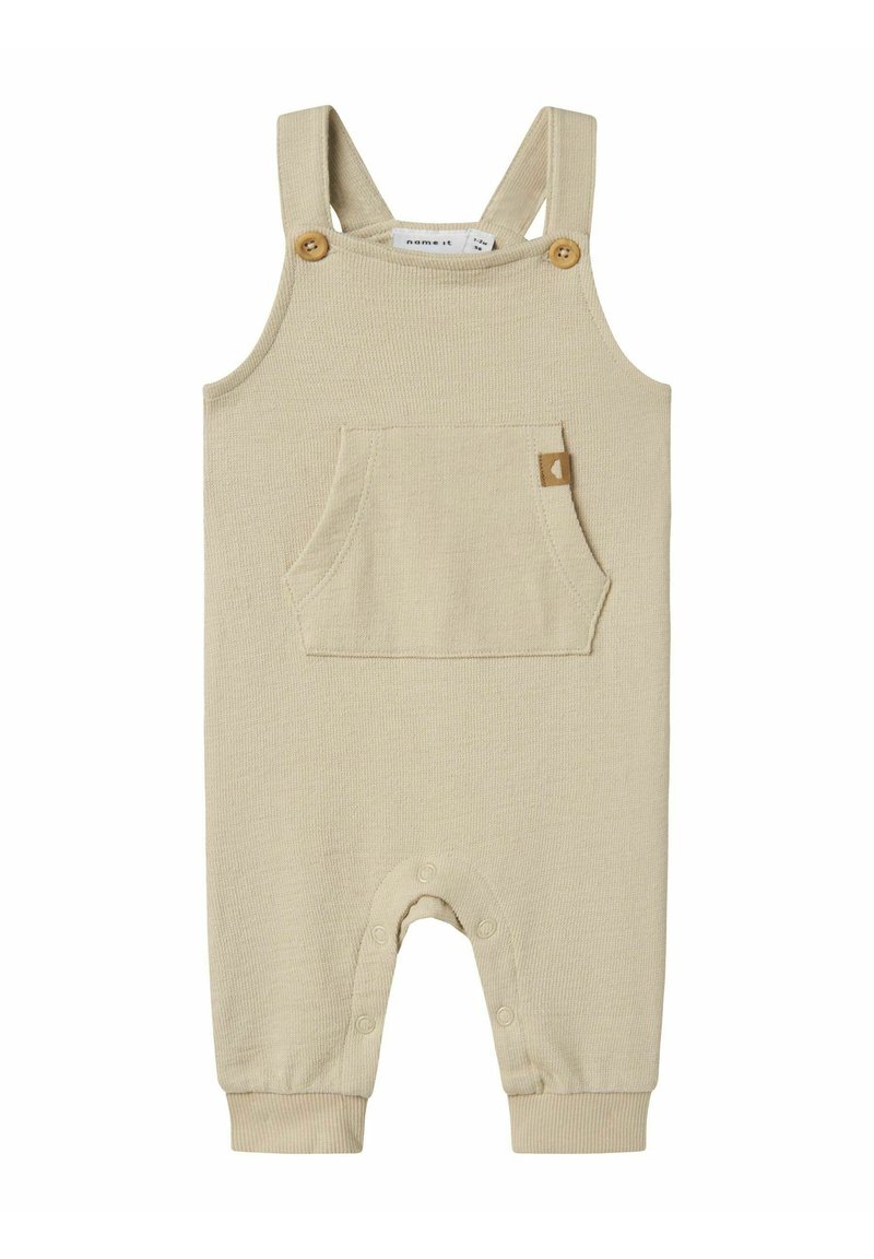 Bodysuit beige à côtes avec bretelles ajustables, boutons en bois, poche frontale et fermetures à pression au bas pour un habillage facile.