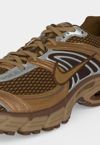 Καφέ και ταμπά αθλητικό παπούτσι Nike με υφασμάτινο διχτυωτό επάνω μέρος, συνθετικές επικαλύψεις και μαλακή σόλα, εμφανιζόμενο από το πλάι και από μπροστά.