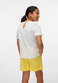 Camicetta bianca a maniche corte con collare in pizzo e dettaglio a chiave sul retro, abbinata a pantaloni corti gialli, caratterizzati da una vestibilità rilassata e una consistenza morbida.
