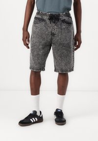 Denim shorts with an elastic waistband and drawstring, in a black and gray mottled pattern, featuring two front pockets and frayed hem.