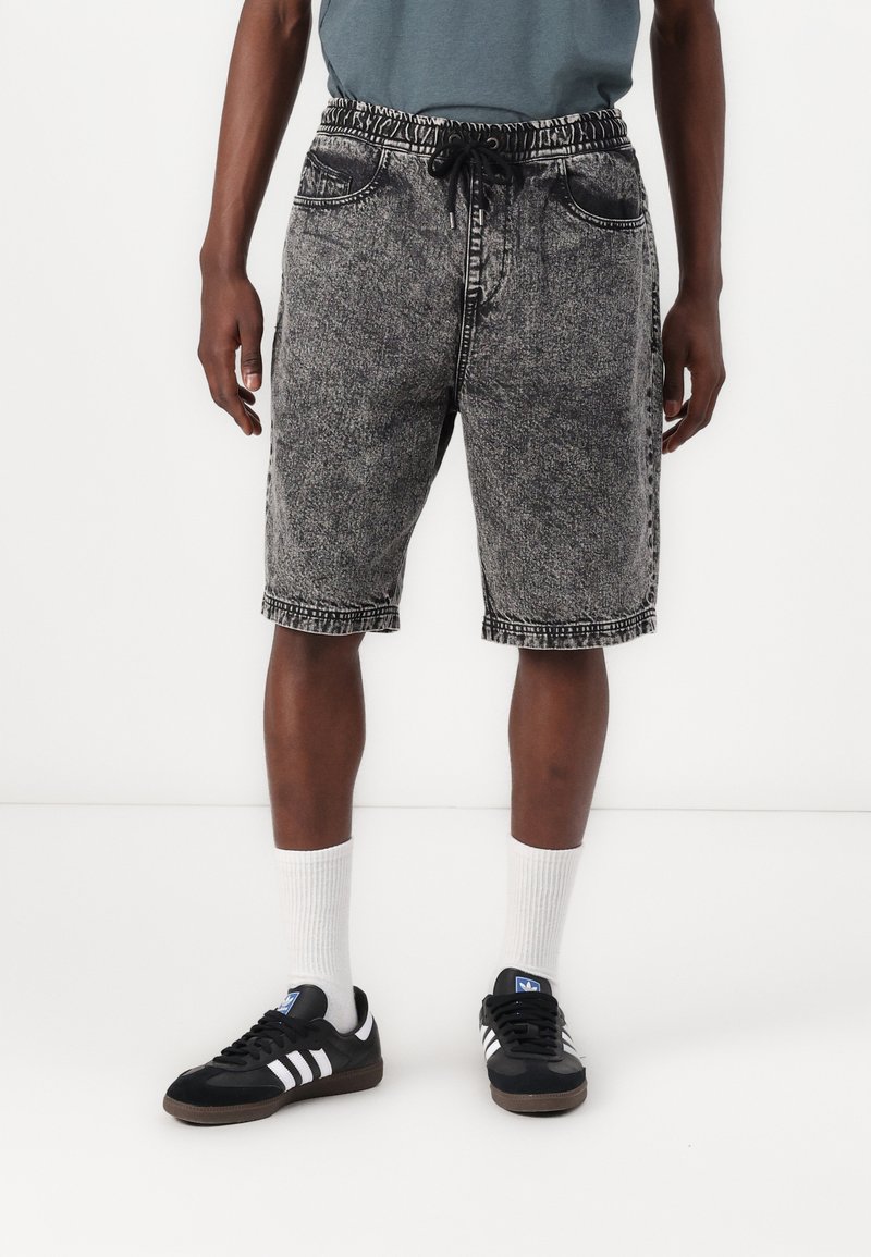 Denim shorts with an elastic waistband and drawstring, in a black and gray mottled pattern, featuring two front pockets and frayed hem.
