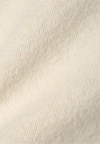 Tissu en laine douce de couleur crème claire avec une texture légèrement duveteuse et tricotée.