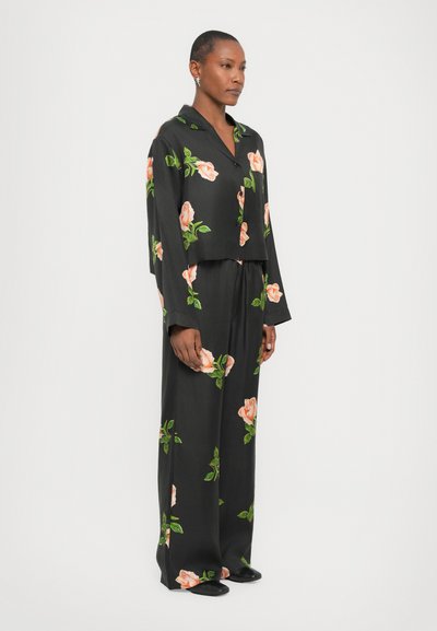 Set da pigiama floreale nero composto da una giacca corta e pantaloni a gamba larga, decorato con stampe di rose rosa e foglie verdi su un tessuto morbido.