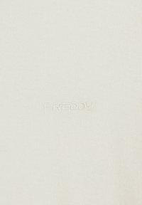 Tessuto bianco a costine con una leggera texture, con un logo ricamato "FREDDY" in filo coordinato vicino al fondo, centrato sull'indumento.