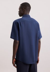 Camicia navy a maniche corte con bottoni, finitura texture, taglio dritto e colletto tradizionale. Design semplice senza motivi.