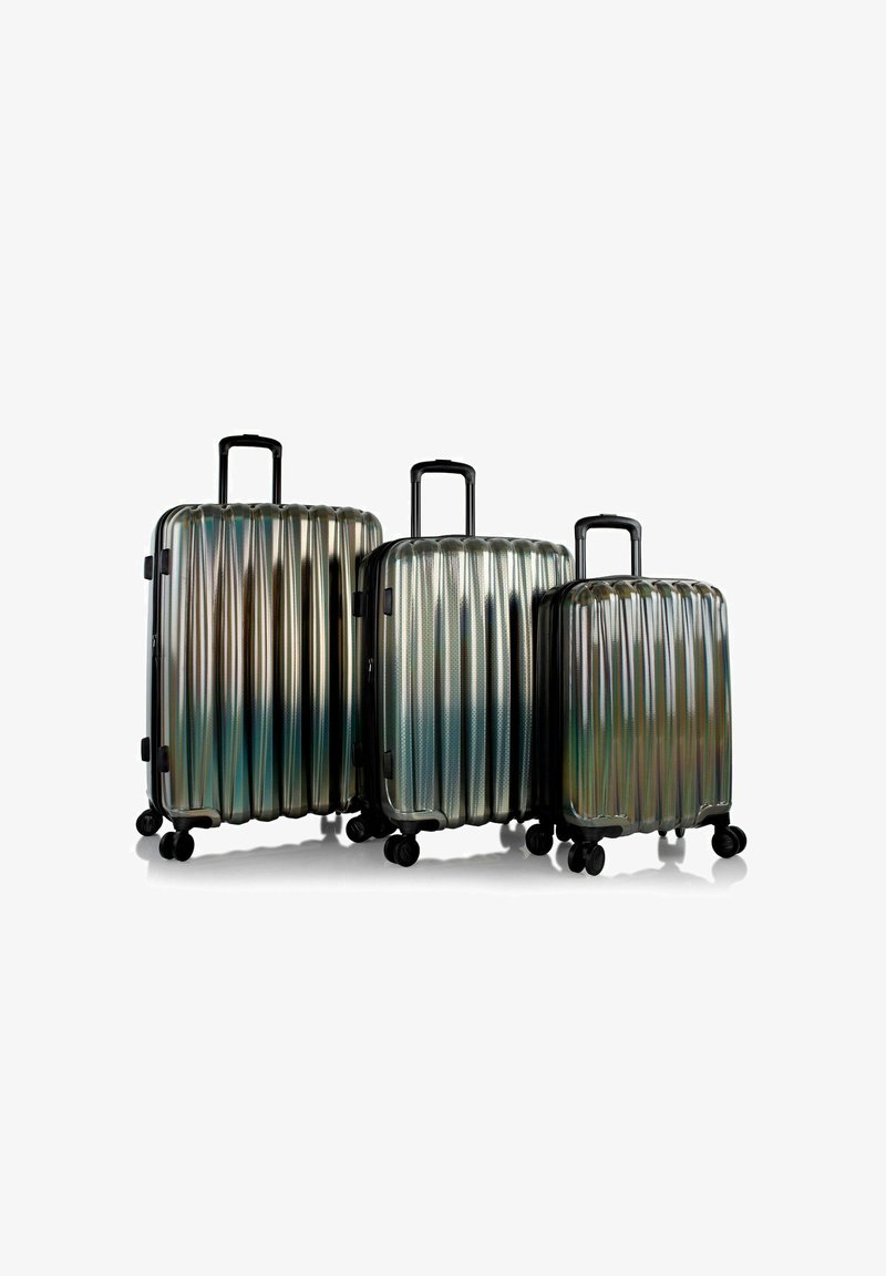 Tre valigie rigide brillanti di diverse dimensioni con motivi a scanalature, dotate di maniglie e ruote nere. Il colore passa dal silver al blu-verde.