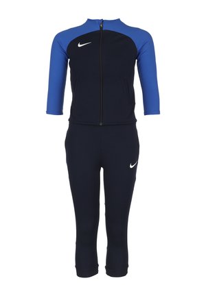 Ensemble de sport bleu marine et bleu avec fermeture éclair, manches trois-quarts et logo Nike blanc bien visible. Fabriqué dans un matériau extensible.