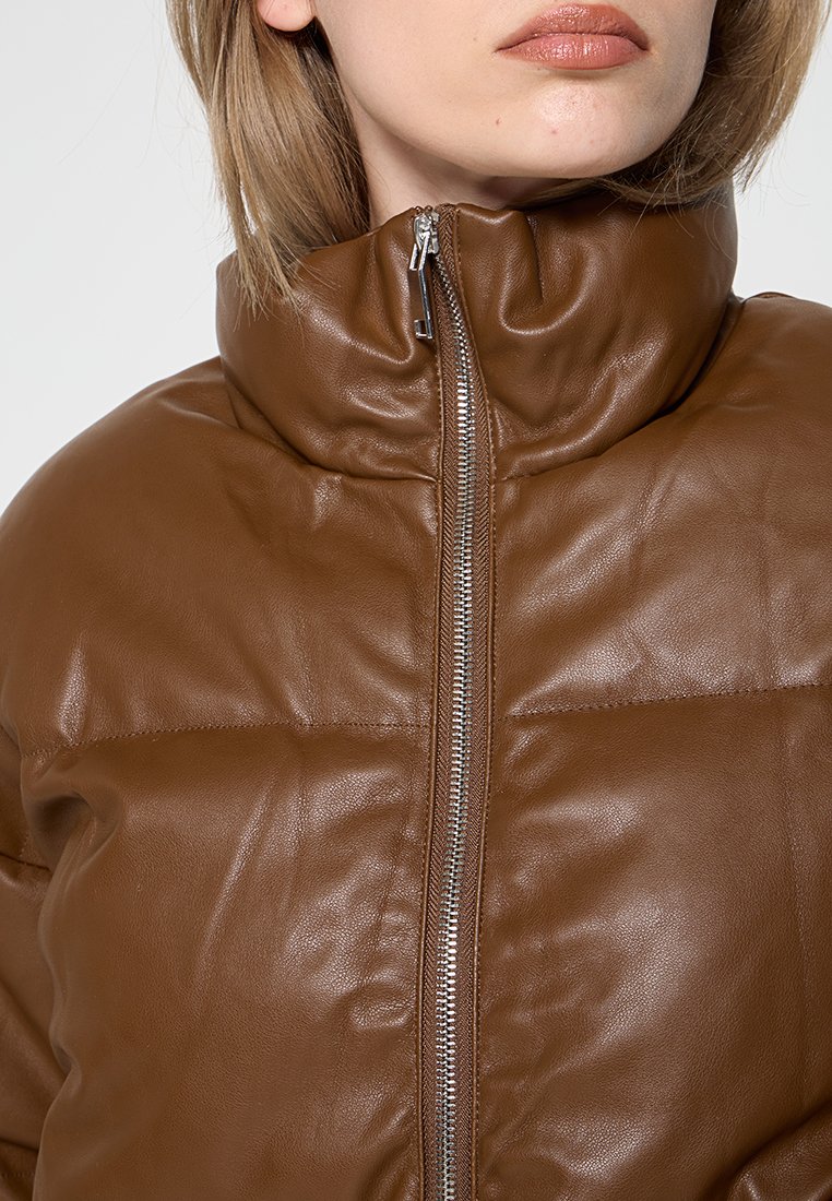 Brązowa skórzana kurtka z wysokim kołnierzem, z zapięciem na zamek z przodu oraz pikowaną fakturą. Gładkie wykończenie z minimalistycznymi detalami.