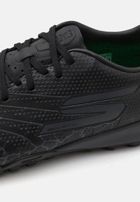 Schwarze Fußballschuhe mit einer strukturierten synthetischen Oberseite, Belüftungsöffnungen für Atmungsaktivität und einer glatten Gummisohle. Bietet dezente Designelemente.