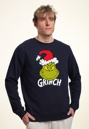 Felpa blu navy in cotone con design del Grinch in stile cartoon e testo "GRINCH" in bianco. Maniche lunghe e collo rotondo.